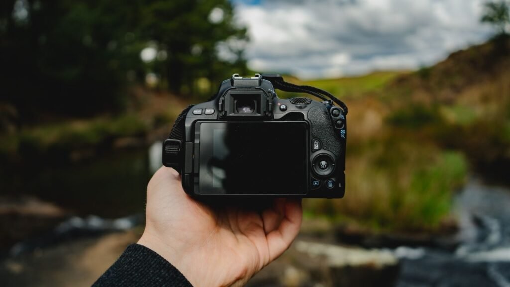 What to Pack for a Kenya Safari: The Ultimate Packing List (2026) Close-up of a hand holding a camera in an outdoor setting with nature in the background.