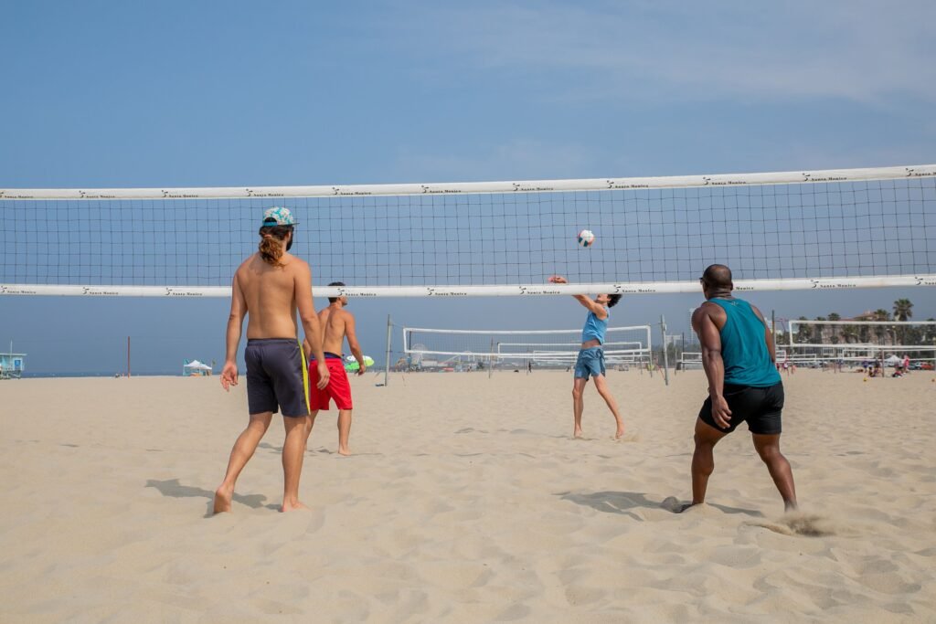 Men playing beach volleyball on a sunny day, highlighting athleticism and leisure.
