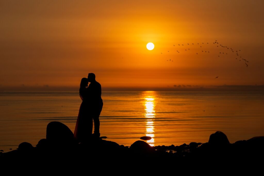 Home A couple silhouettes embrace during a stunning ocean sunrise.