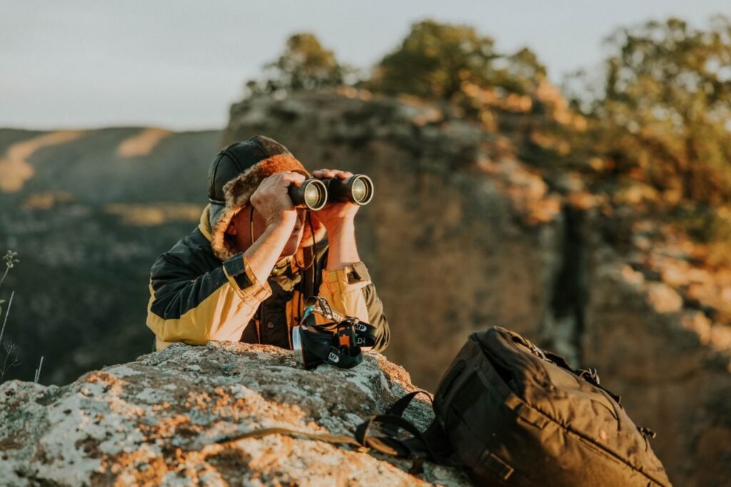 What to Pack for a Kenya Safari: The Ultimate Packing List (2026) An adventurer observes through binoculars in a picturesque canyon landscape during dusk.
