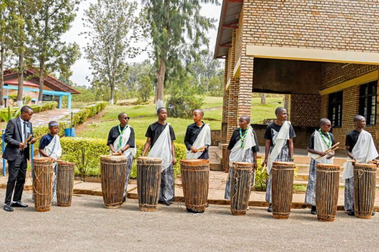 Home A vibrant outdoor traditional drumming performance in Rwanda with a group of musicians.