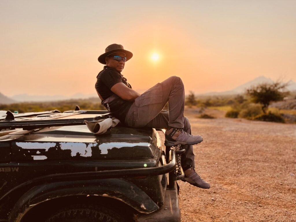What to Pack for a Kenya Safari: The Ultimate Packing List (2026) Adventure enthusiast relaxing on a Jeep during a stunning sunset in the wilderness.