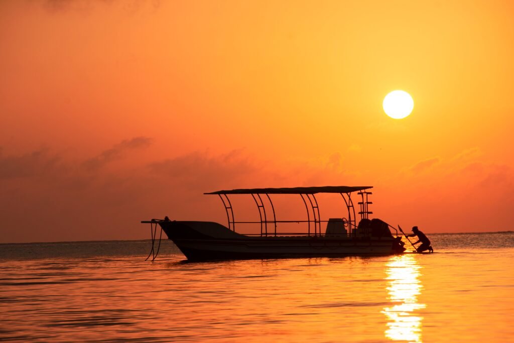 Home Silhouette of a boat and man during a stunning sunset in Mombasa, Kenya.