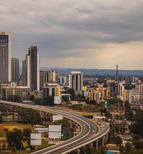 Aerial view of Nairobi's modern skyline and expressway under cloudy skies.