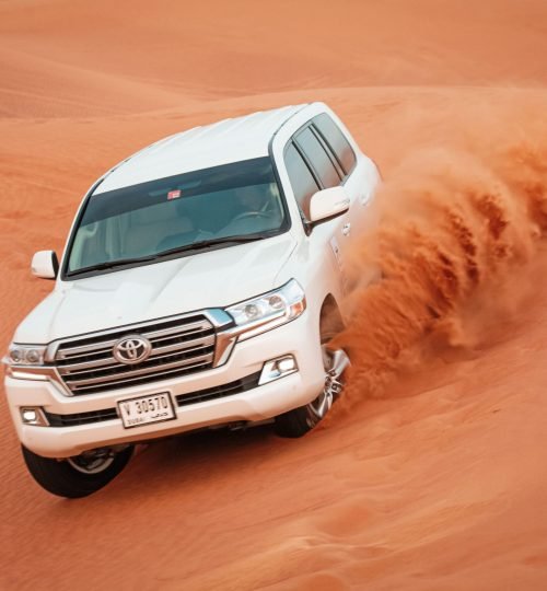 A Toyota Land Cruiser navigates the sand dunes of Dubai, showcasing its off-road capabilities.